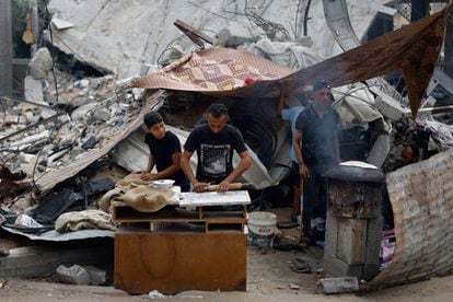 Palestinos preparan comida al lado de un edificio destruido, este lunes en Jan Yunis.  