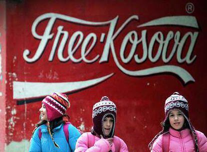 Tres niños pasan ante una pintada con la imagen de Coca-Cola que aboga por un Kosovo libre, ayer en Mitrovica.