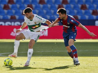 El delantero del Elche Lucas Boyé protege el balón ante el defensa del Levante Sergio Postigo este sábado en el estadio Ciutat de València.