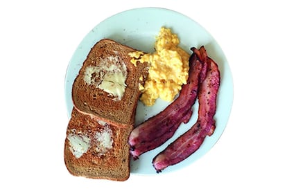 Un plato con tostadas, bacon y huevos.