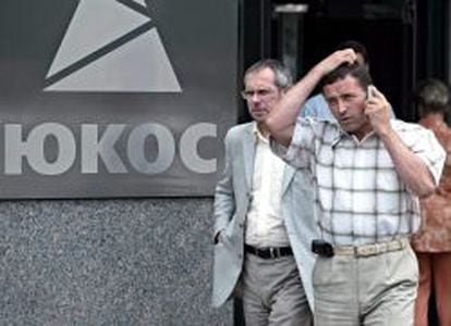 Fotograf&iacute;a de archivo fechada el 2 de agosto de 2004 en la que se muestra un grupo de personas que pasa por delante del logo de Yukos en la sede de la petrolera rusa en Mosc&uacute; (Rusia). 