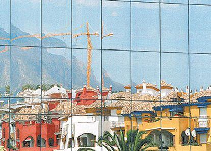 Los cristales de un edificio de Marbella reflejan la realidad de la capital turística de la Costa del Sol: las grúas conquistan todos los espacios libres.