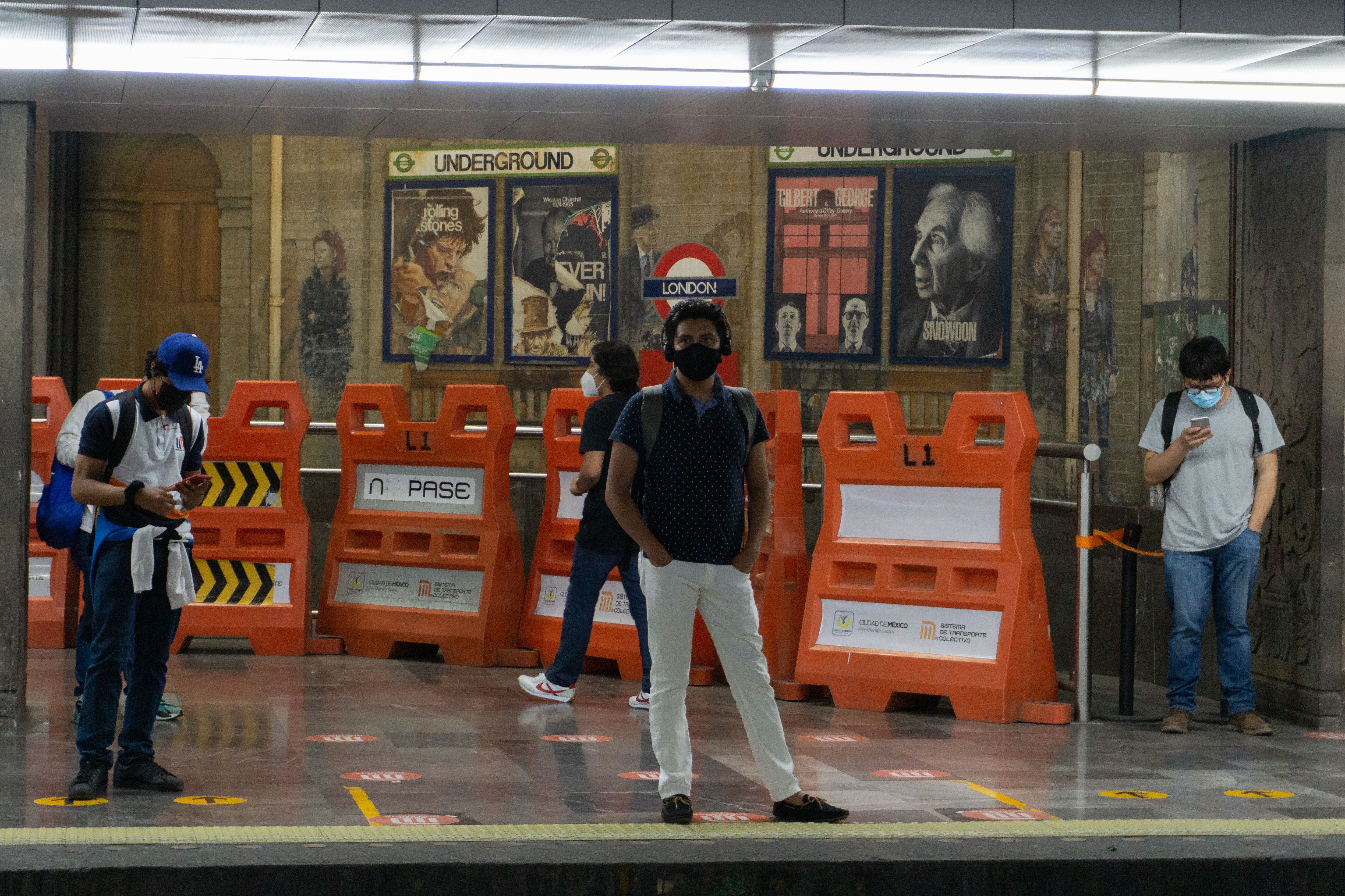 Usuarios en la estación de metro Insurgentes delante de los murales de Cauduro. 