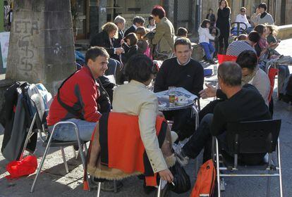 Varias personas disfrutan del sol otoñal en una terraza de la plaza del Ayuntamiento de Mondragón.