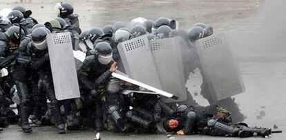 Policías antidisturbios tratan de protegerse durante el enfrentamiento en Biskek (Kirguizistán) contra la oposición.