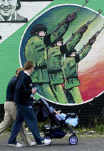 Una familia pasa delante de un mural del IRA en Belfast, en julio de 2002.