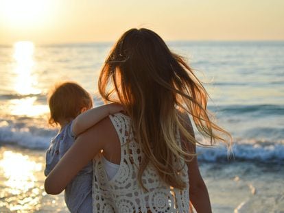 Una madre abraza a su hijo frente al mar.