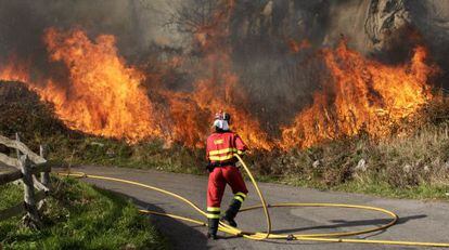 Un bombero apaga un incendio en Ribera de Arriba (Asturias), este lunes.