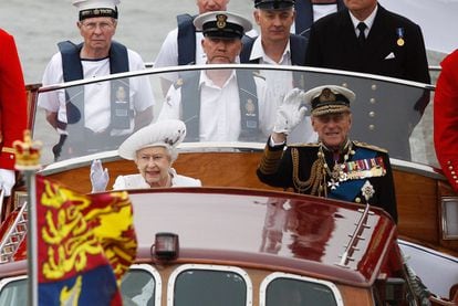 La reina Isabel y el príncipe Philip saludan desde el bote durante el desfile ceremonial por el Támesis.