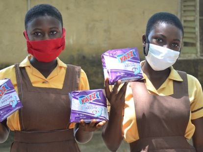 Dos jóvenes sujetan varios paquetes de compresas en Pediatorkope (Ghana).
