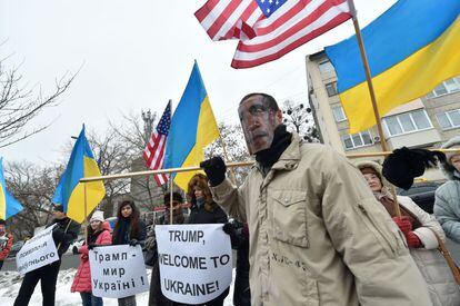 Un hombre con una máscara del presidente saliente, Barack Obama, se pasea frente a otras personas que sostienen pancartas dando la bienvenida a Donald Trump, delante de la embajada de los Estados Unidos, en Kiev (Ucrania).