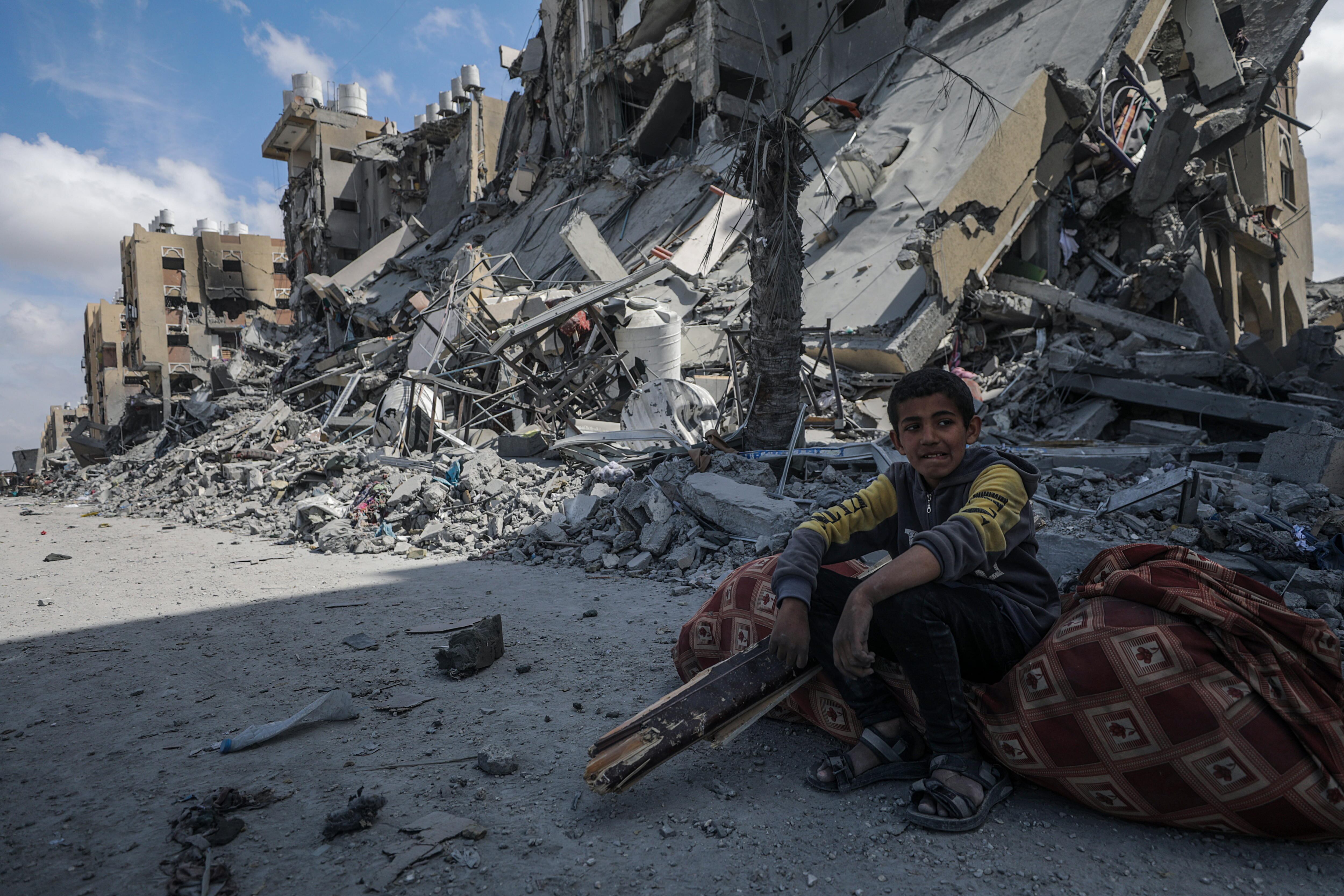 Un niño palestino sentado en las ruinas de un bloque de viviendas destruido en los bombardeos, en Jan Yunis, en el sur de la franja de Gaza.