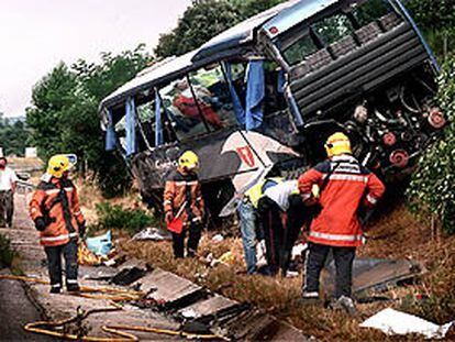 Los bomberos inspeccionan el lugar en el que quedó  el autocar tras la colisión con el  camión.