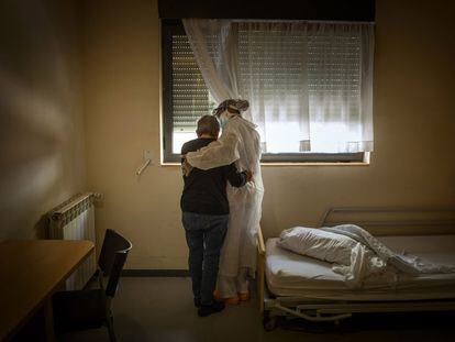 Una anciana y una trabajadora se abrazan en la habitación en la que la primera permanece confinada, en una residencia de Barcelona en abril de 2020.