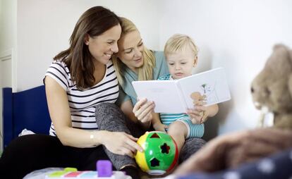 Dos madres leen un cuento a su hijo.