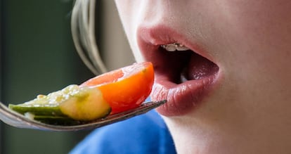 Una niña come frutas y verduras.