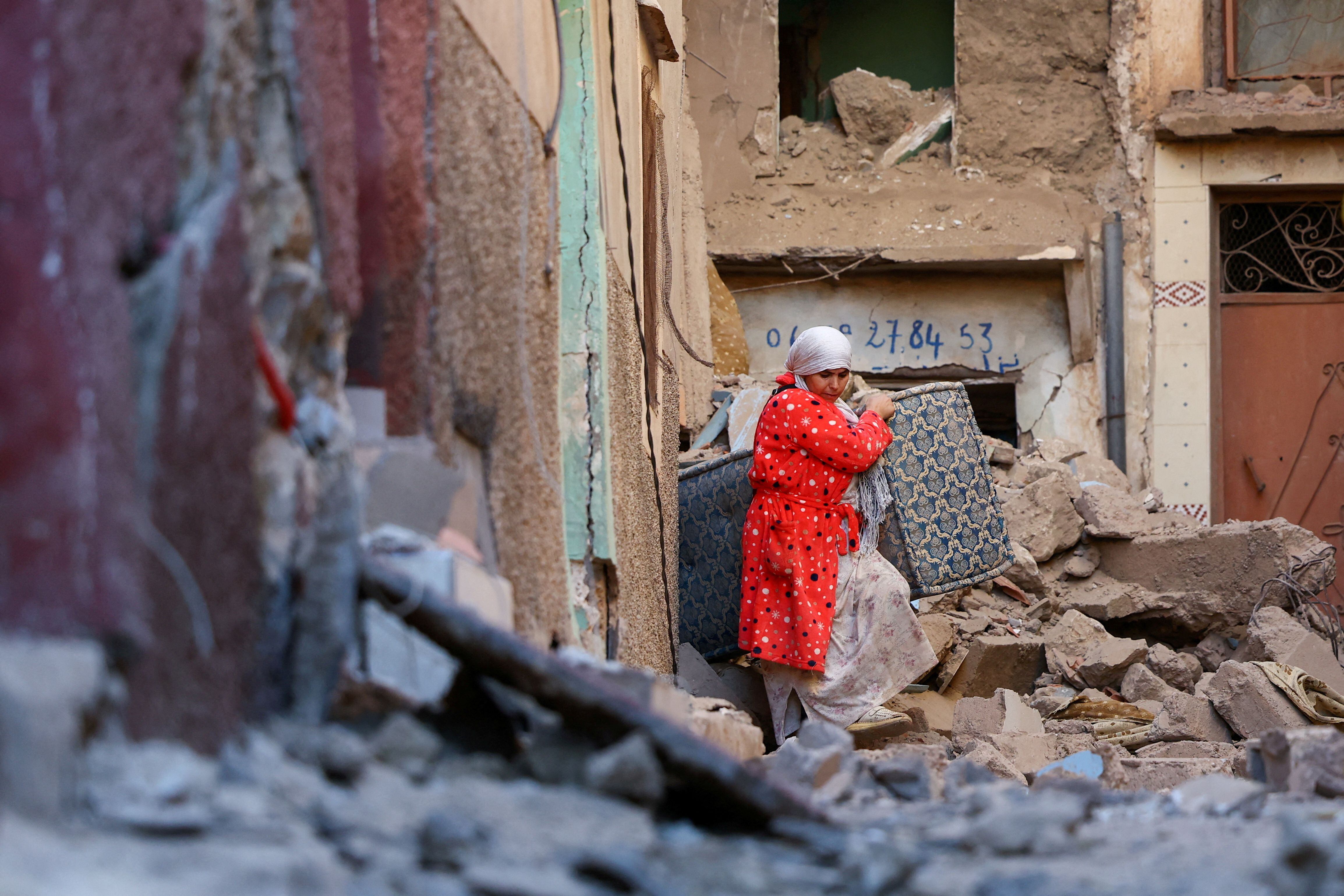 Una mujer saca sus pertenencias de un edificio dañado tras el terremoto en Mulai Brahim.