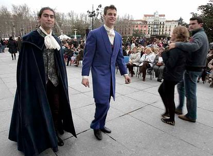 Dos figurantes vestidos de época recorren la plaza de Oriente entre los asistentes a las funciones de ópera en la calle.