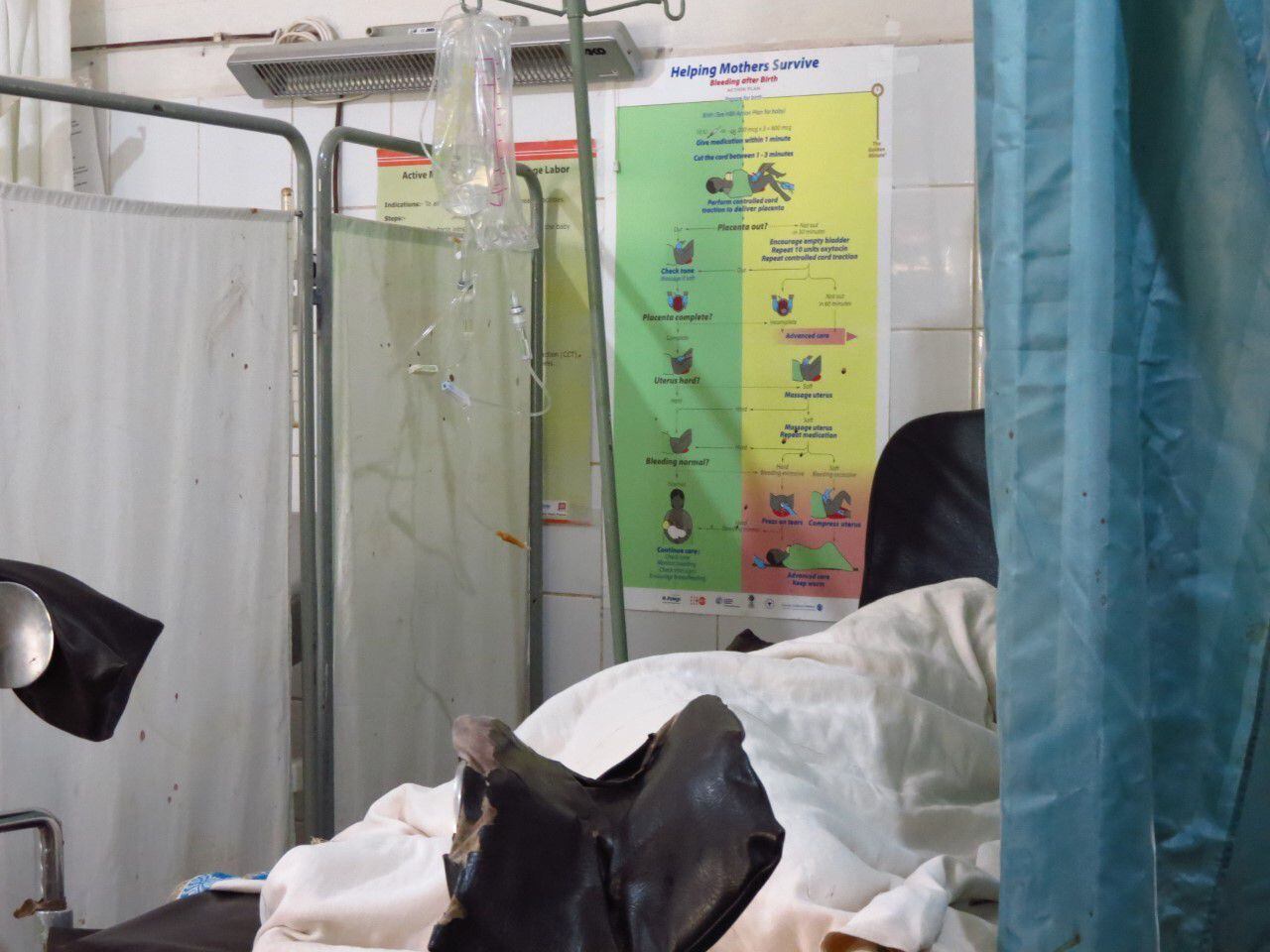 Una mujer descansa después de dar a luz en la cama de partos del hospital rural de Gambo. En la pared observamos el algoritmo de manejo de la hemorragia posparto del curso realizado a las matronas del centro para disminuir la principal causa de muerte materna en la región.