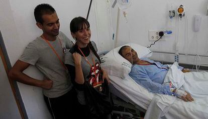 Francisco Moreno, en la cama, ha donado el riñón a su nieto, hijo de Sabino Moreno y su esposa, Alexandra Corretge, de pie, en el hospital donde se ha llevado a cabo el trasplante.