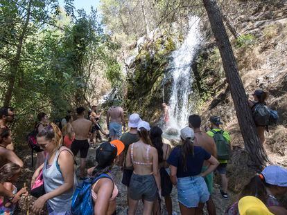 Numerosos turistas esperan su turno para refrescarse en una cascada en el río Chíllar, en Nerja (Málaga).