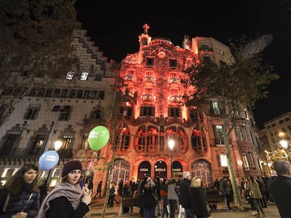 Unes noies passen per davant de la Casa Batlló, il·luminada de vermell.