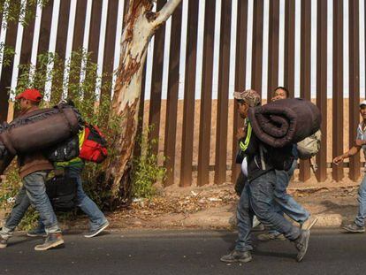 Migrantes caminando en los alrededores del muro fronterizo