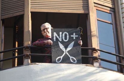 Un vecino de Valencia muestra una pancarta contra los recortes desde el balcón de su vivienda.