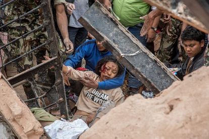 Trabajadores del servicio de emergencia rescatan a una mujer de las ruinas de la torre Dharara, en Katmandú, derrumbada tras el terremoto.