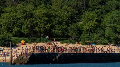 Grupos de jóvenes hacen cola para saltar al mar en el espigón de la playa de la Magdalena de Santander este lunes.