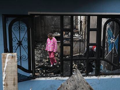 Una mujer camina entre los restos quemados de una casa en Santa Fe, al oriente de Bogotá (Colombia), este viernes.