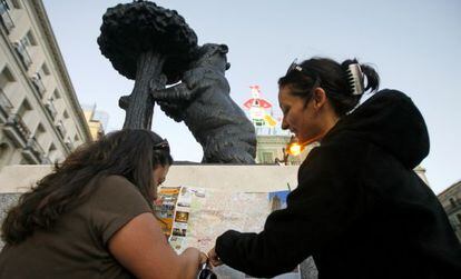 Dos turistas consultan un mapa en la Puerta del Sol.