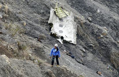 Un miembro de los servicios de rescate camina al lado del mayor resto de fuselaje del avión siniestrado, en el que se aprecian tres ventanillas, entre millones de fragmentos del aparato esparcidos por una amplia área de alta montaña en los Alpes franceses.