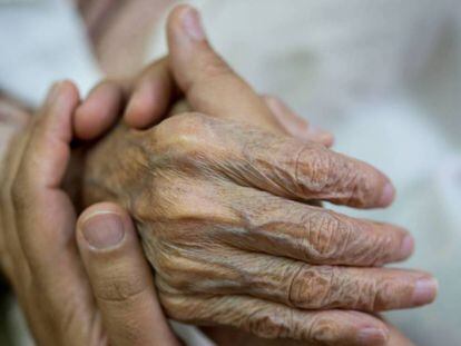 Una persona da la mano a un anciano. 