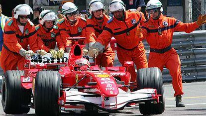 Los auxiliares de pista empujan el coche de Schumacher hacia el garaje.