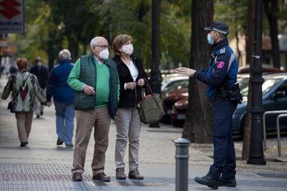 Un agente de la Policía Local de Madrid informa a una pareja sobre las medidas contra el coronavirus.