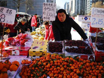 Un vendedo de fruta espera en un mercado local de Pek&iacute;n (China