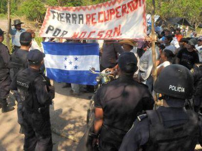 Polic&iacute;as antidisturbios montan guardia mientras un grupo de campesinos abandonan una parcela que hab&iacute;an ocupado al norte de Tegucigalpa. 