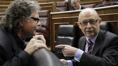 El ministro de Hacienda, Cristóbal Montoro, sentado, conversa con el diputado de ERC Joan Tardá, en el hemiciclo.