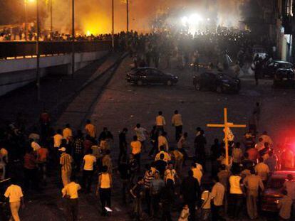 Cristianos coptos (abajo) se enfrentan a fuerzas de seguridad egipcias (arriba) mientras una multitud corre en un puente durante protestas llevadas a cabo frente al edificio de la radiotelevisi&oacute;n en El Cairo.