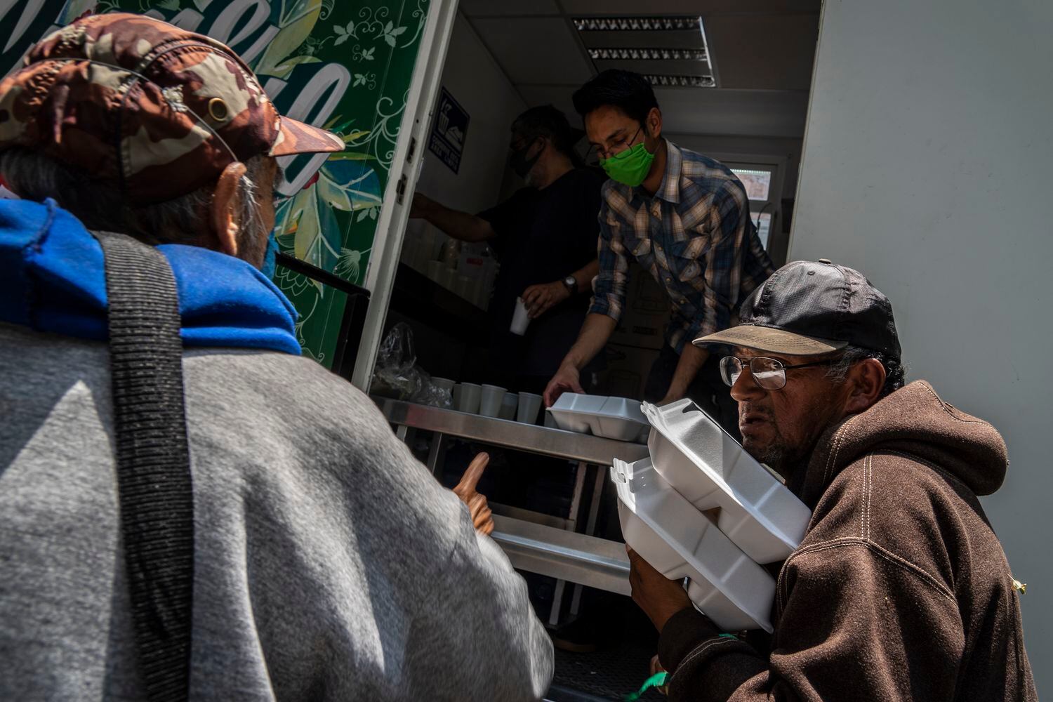 Varios hombres reciben comida de forma gratuita en el Parque de los Venados de la Ciudad de México.