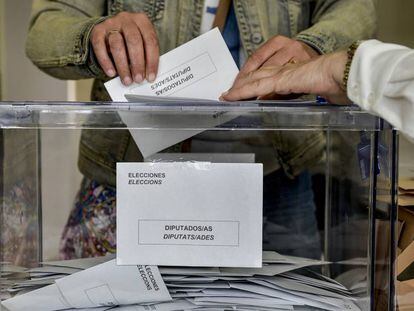 Una persona deposita su voto en una urna electoral, en Cataluña.