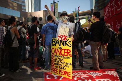 Un hombre sujeta una pancarta contra los "excesos del capitalismo de libre mercado" en las protestas en Hong Kong.