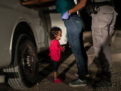 La niña Yana, de Honduras, llora mientras su madre, Sandra Sánchez, es cacheada por un policía estadounidense de fronteras en McAllen (Texas).