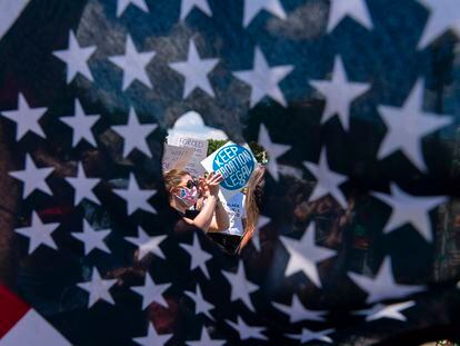 A través de un agujero en una bandera estadounidense, se observa a activistas que sostienen un letrero que lee "Mantengan legal el aborto", el 25 de junio de 2022, en Washington D. C. (EE.UU.).