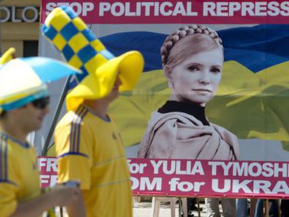 Aficionados ucranianos pasan ante un cartel de Timoshenko. 
