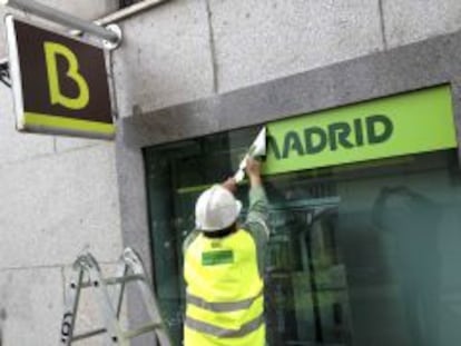 Un trabajador sustituye el logotipo de Caja Madrid por el de Bankia en una sucursal.