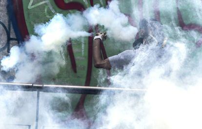 Un manifestante lanza un bote de gas lacrimógeno durante los disturbios ocurridos con motivo del paro nacional convocado por la oposición.