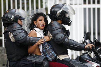 Miembros de la policía nacional de Venezuela detienen a una mujer y se la llevan en moto, durante los conflictos provocados por las protestas contra el Gobierno.