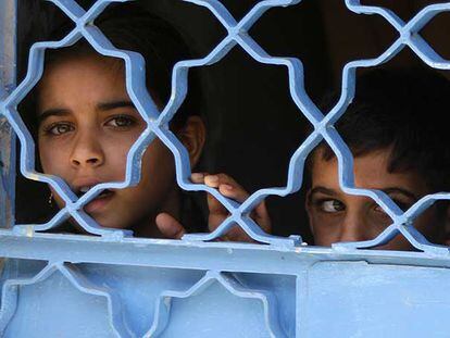 Dos niños observan una patrulla de soldados estadounidenses en Bagdad desde la puerta de su casa.